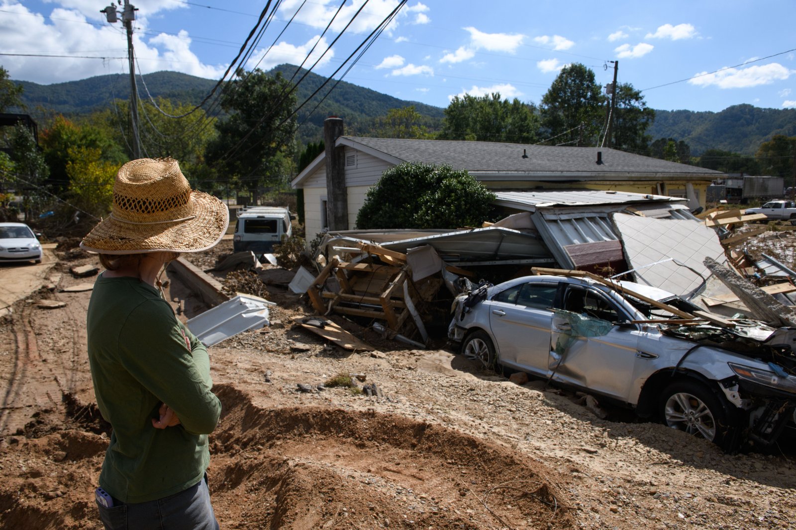 Emily Ogburn looks at her partner's home after it was destroyed by flooding last October in Swannanoa, North Carolina. A new report predicts that tens of millions of Americans will relocate within the U.S. to areas less vulnerable to climate change in the next three decades