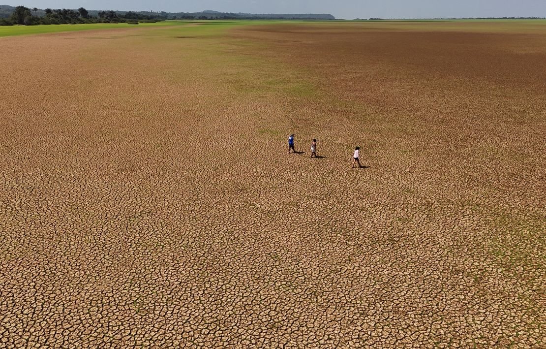 People walking on the dry bed of the Tapajos river during an intense drought, in Tapajos National Forest, Para state, Brazil October 10, 2024.