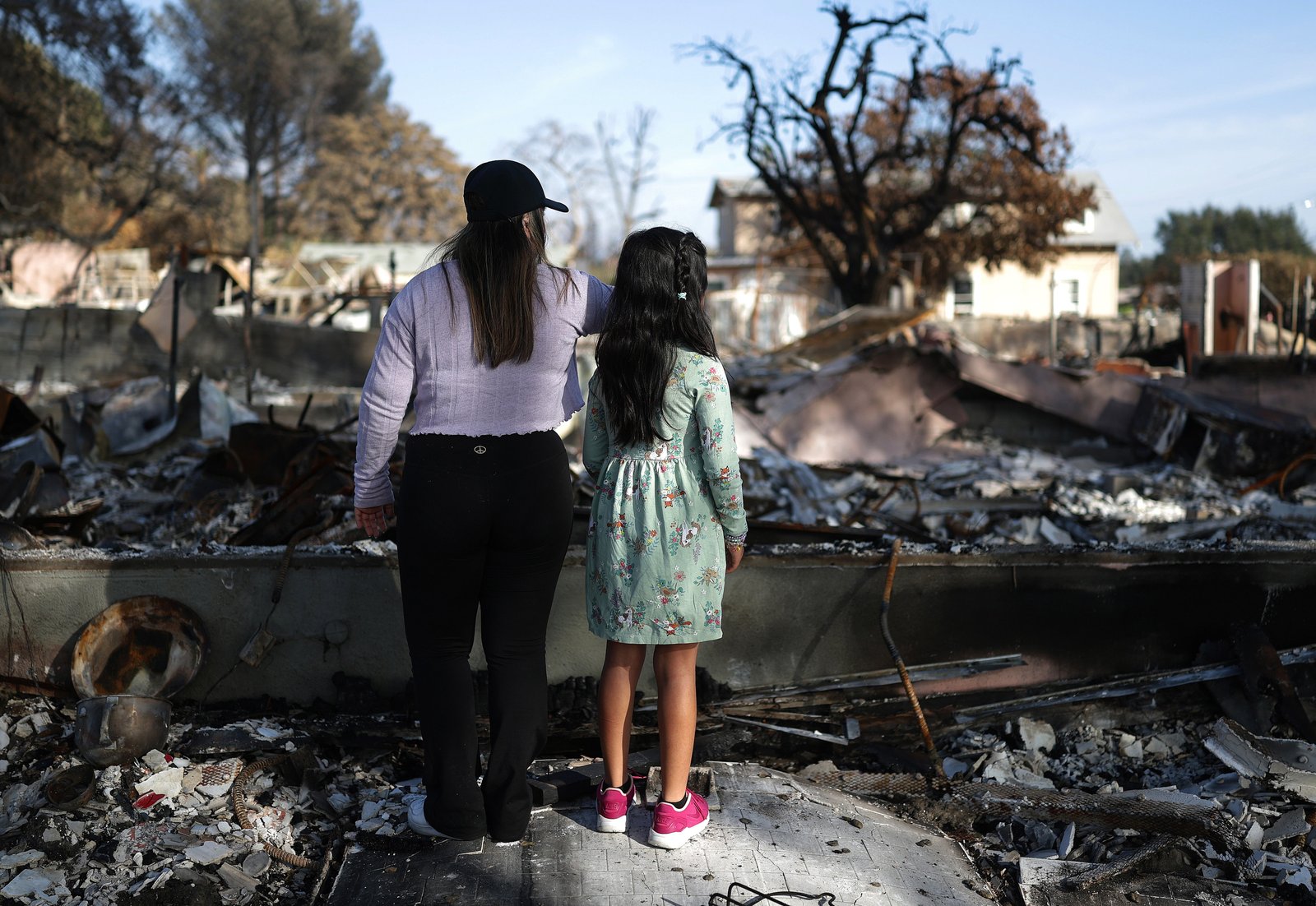 Sisters Lesly and Rose Garrido-Lopez view the remains of their home which burned in the Eaton fire on Sunday in Altadena, California. Thousands of homes burned in the blaze, which was worsened by climate impacts